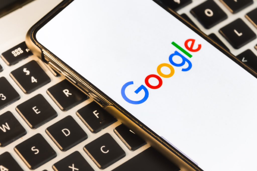 imagem de um teclado de computados com celular sobre ele na pagina inicial do google site de busca