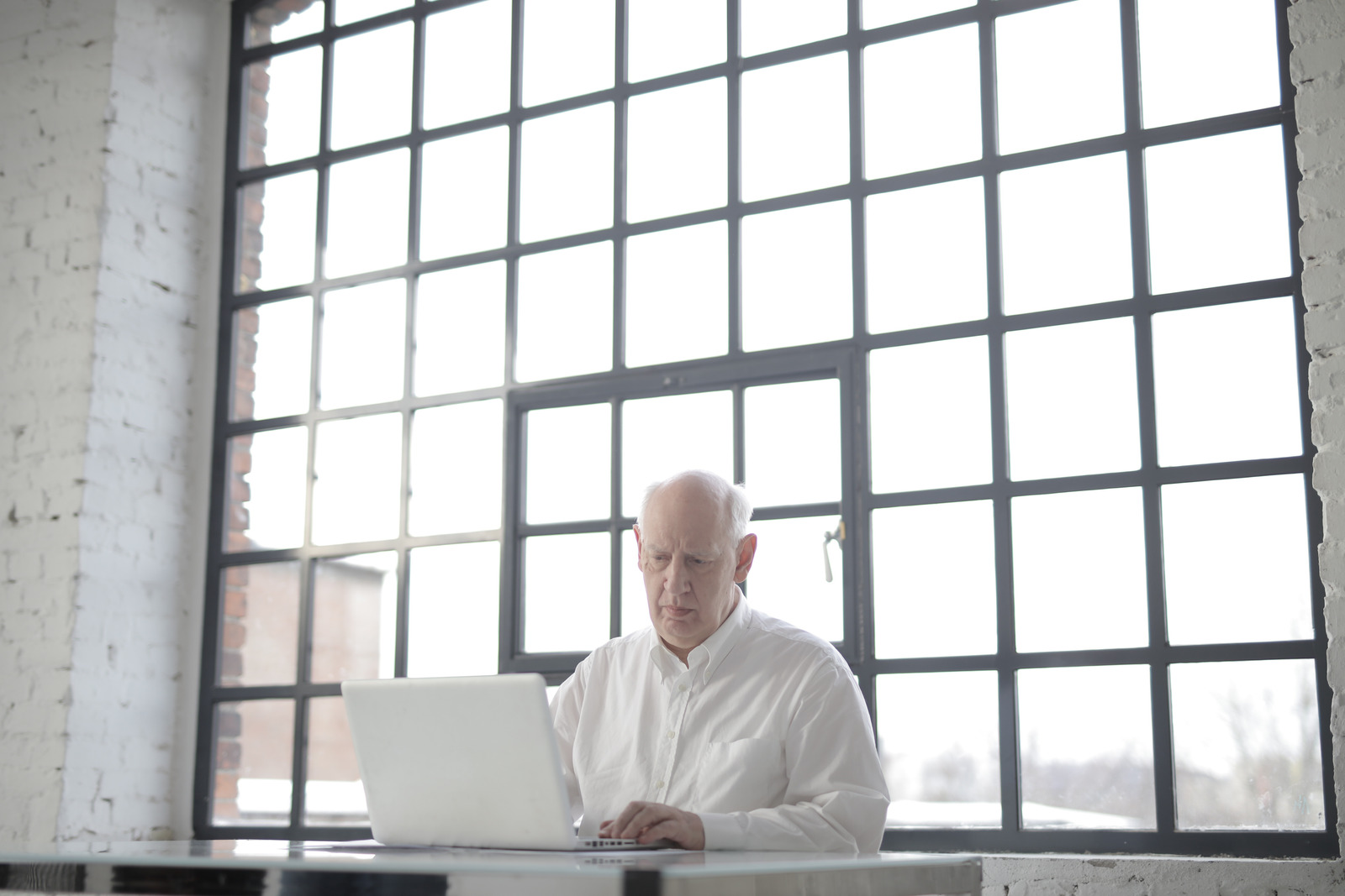Canva – Man in White Shirt Sitting by the Table Using Macbook