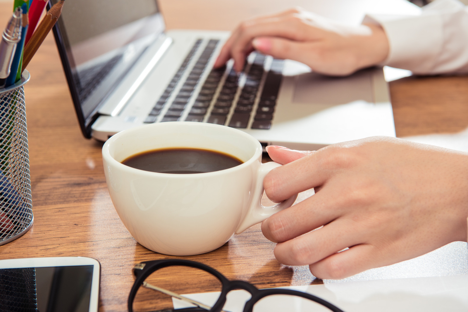 Businesswoman using laptop and drink coffee at desk