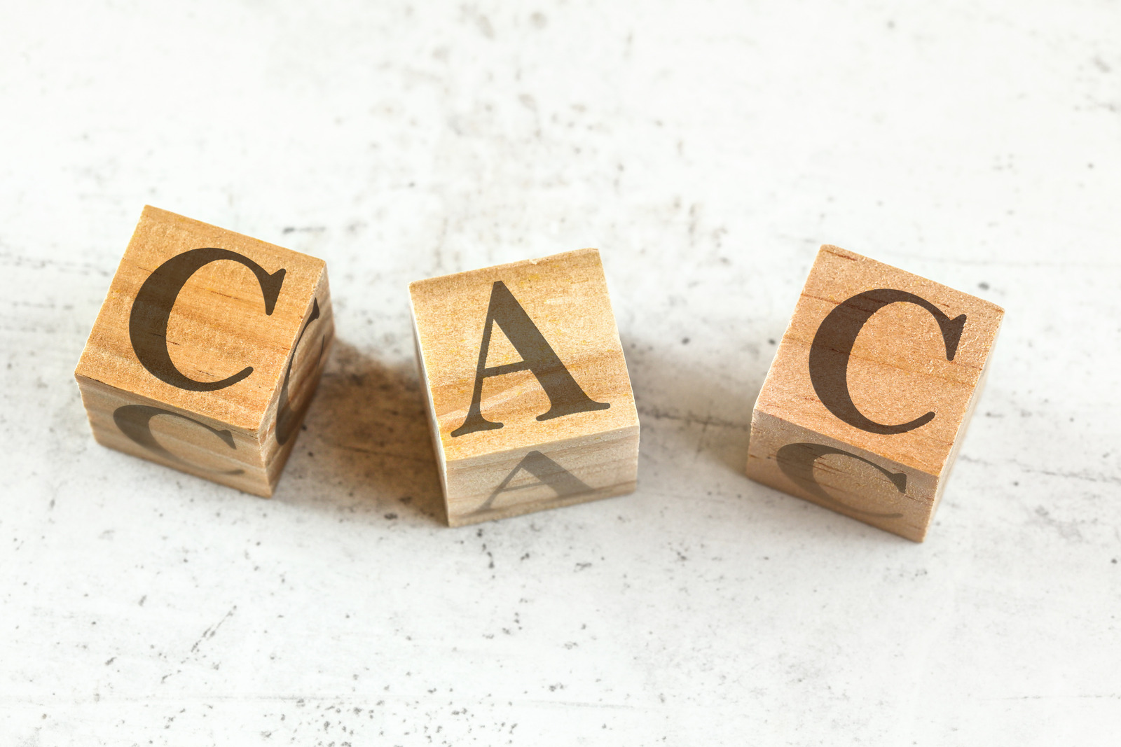 Three wooden cubes with letters CAC stands for Customer Acquisition Cost on white board.